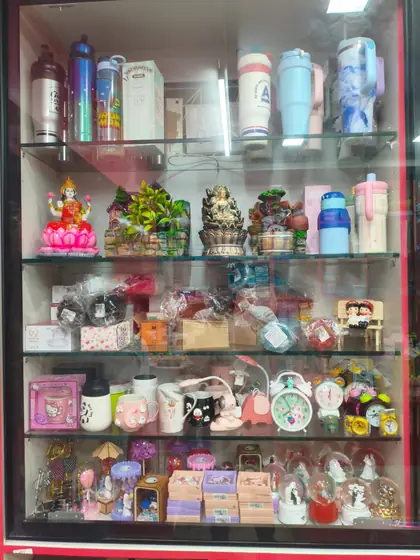Glass showcase of gift items including mugs, bottles, clocks and showpieces